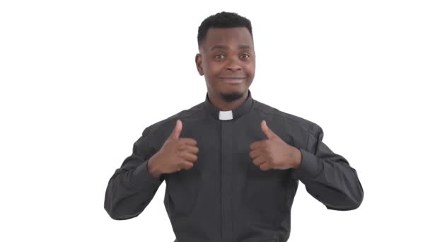 非洲面带微笑的牧师的画像 双手竖起大拇指 把大拇指贴在胸前 与白色背景隔离 — 图库视频影像