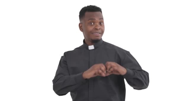 滑稽的黑人牧师的画像 用象征爱情的手指在白色背景上做着心形的手势 — 图库视频影像