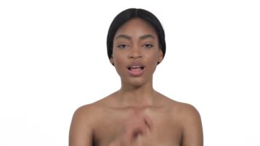 Çıplak omuzlu, dudaklarına hafifçe dokunan ve kameraya poz veren seksi genç kadın. İzole edilmiş, beyaz arkaplanda