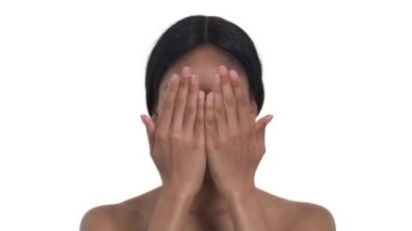 Güzel, neşeli bir Afrikalı kadının portresi avuçlarıyla yüzünü kapatıp onu açıyor. Olumlu, mutlu yüz ifadesi olan bir model. Gerçek duygular