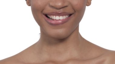 Dudaklarını ısıran güzel bir mankenin yakın çekimi. Afrikalı kadın kusursuz beyaz dişleriyle gülümsüyor. İzole edilmiş, beyaz arkaplanda