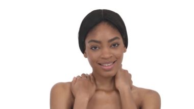 Çıplak omuzlu baştan çıkarıcı Afrikalı kadın kameraya poz veriyor, nazikçe boynuna dokunuyor. Kamera harikulade bir sunum. İzole edilmiş, beyaz arkaplanda