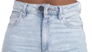 Bir kızın bir düğmeyi açıp, kot pantolonla uçtuğunu görmek. Yakın plan. İzole edilmiş beyaz arkaplan.