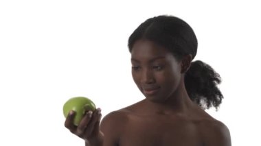 Beyaz arka planda yeşil elma yiyen genç siyahi kadın portresi