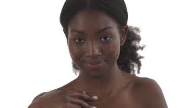 Afrikalı genç bir kadının portresi elini yavaşça omuzlarından çenesine ve boynuna dolayarak beyaz arka planda vücudunu okşuyor.