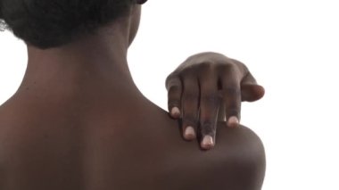 Beyaz arka planda elini omzundan boynuna kadar götüren siyah kadının arkası.