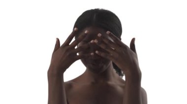 Siyahi kadınların portresi beyaz arka planda yavaşça ellerini yüzlerinden ayırıyor.