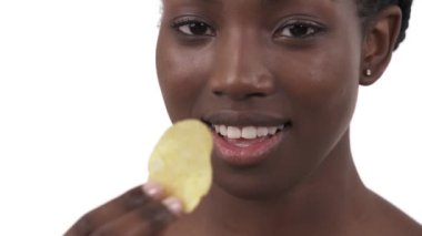 Zevkle çıtır çıtır yiyen genç zenci kızın yakın plan portresi. Sağlıksız beslenme. Beyaz arkaplanda izole