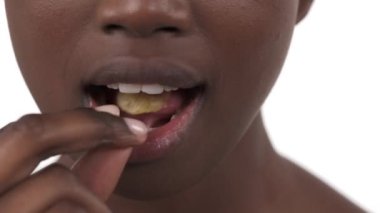 Genç Afrikalı kızın yüzünün alt kısmının zevkle cips yediği son derece yakın plan. Sağlıksız diyet. Beyaz arkaplanda izole