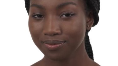 Kameraya bakıp başını sallayan genç siyahi kadının yakın plan portresi. Beyaz arkaplanda izole