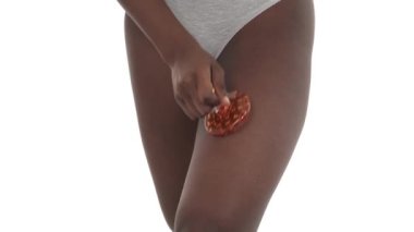 Afrikalı bir kadın bacağına, portakal kabuğunun önlenmesi için antiselen vücut fırçasıyla masaj yapıyor. Beyaz arka planda izole edilmiş. Güzellik ve vücut bakımı kavramı.