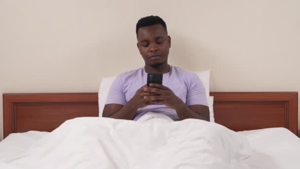 Afrikalı Bir Adamın Portresi Yatakta Uzanıyor Telefonda Kayıt Yapıyor Beyaz — Stok video