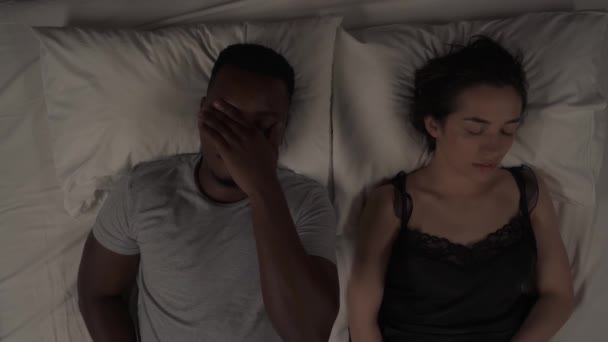 夜间躺在床上的混血夫妇的头像 非洲男人捂着耳朵 忍受着睡着的白人女朋友的呼噜声 — 图库视频影像