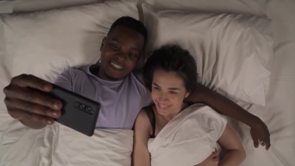 Geceleri Yatakta Uzanan Akıllı Telefonuyla Selfie Çeken Melez Çiftlerin Iyi — Stok video