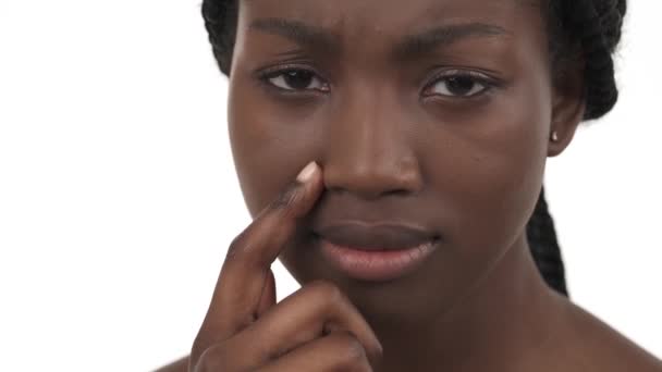 若いアフリカ系アメリカ人の少女がカメラを見て鼻をこする姿がクローズアップされている 白地に隔離された — ストック動画