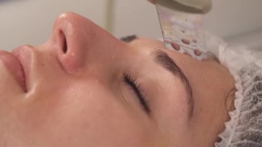 Profesyonel ekipmanlarla yapılan ultrasonik derin yüz temizleme prosedürünün yakından görüntüsü. Yaşlanma önleyici cilt tedavisi