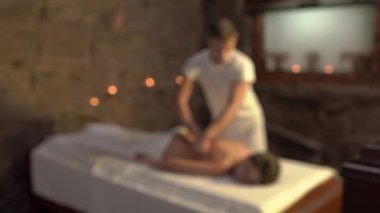 Terapistin müşteriye sırt masajı yaptığı kamera görüntülerine yaklaşıyoruz. Spa ve sağlık konsepti. Bulanık arkaplan, seçici odak