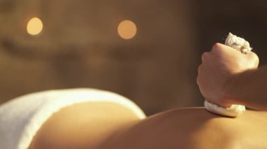 Profesyonel bir masörün, bitkisel sıkıştırılmış top masajı yaptığı yakın plan fotoğraf. Spa ve sağlık konsepti. İzole edilmiş, bulanık arkaplanda