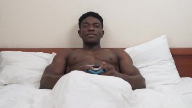 Yatakta uzanmış konsol oynayan siyah bir adamın portresi. Afrikalı bir kadının bacakları kameranın önünde beliriyor ve külotunu çıkarıyor. Çenesini düşüren adam joystick 'i fırlatıyor..