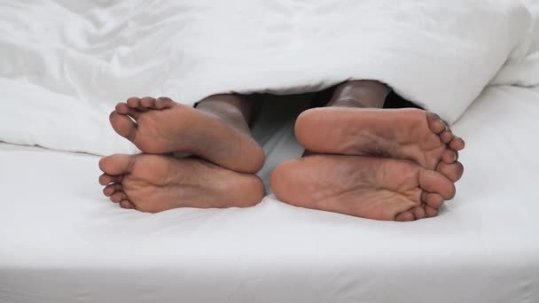 黒のカップルのダンスのつま先で素足の非常に近い 白い毛布の下を見て 愛と家族の概念 — ストック動画