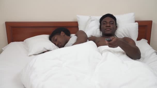 아프리카 침대에 남자는 콘으로 채널을 바꾸고 로운걸찾고 잠자는 여자를 깨우려고 — 비디오