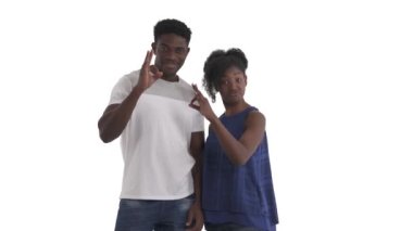 Genç Afrikalı Amerikalı bir çiftin portresi başparmak ve işaret parmaklarını bir daire içinde birleştiriyor ve beyaz arka planda izole edilmiş iyi işaretleri gösteren bir parmak daha tutuyor.