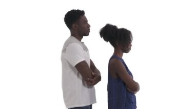 Afrikalı çiftin göğüs hizasında ellerini kavuşturup sağ tarafa baktıkları ve beyaz arka planda izole edilmiş kameraya baktıkları yan görüntü.