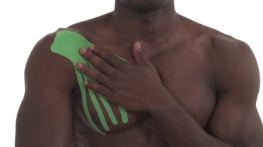 Tanımlanamayan Afrikalı sporcunun dairesel omuz mp4 hareketleri, yaralanmış omzuna kineziyoloji bandıyla dokunması. Beyaz arkaplanda izole