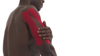 Yaralı trisepse dokunan bir sporcunun yakın plan görüntüsü Kinesio bandıyla bantlanmış. Spor yaralanması kinesio tedavisi. Beyaz arkaplanda izole