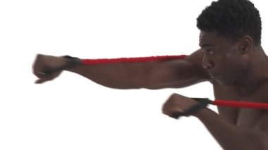 Yüksek yoğunluklu bir Afrikalı dövüşçünün direnç bandı kemeriyle yumruk çalışmasının yan görüntüsü. Profesyonel spor konsepti. Beyaz arkaplanda izole edilmiş, yakın çekim alanı kopyala