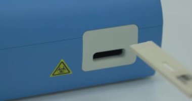 Hızlı covid-19 testini kapat. Tanımlanamayan laboratuvar asistanı test cihazını yerleştiriyor. Antijen testi için hızlı bir yöntem. Biyolojik tehlike işareti.