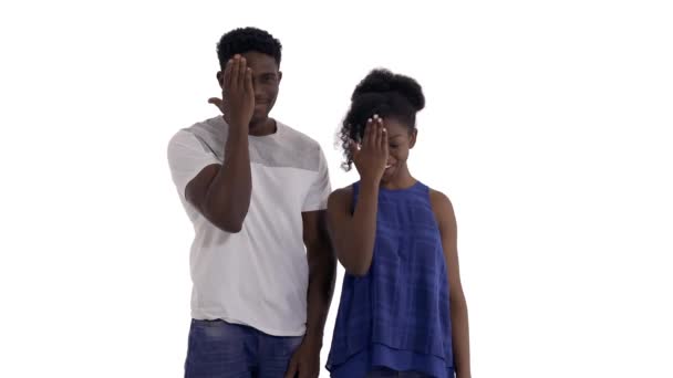 这对年轻的黑人夫妇在偷窥表演的肖像 把他们的脸藏在手后面 然后把它拿走 在白色背景下隔离 — 图库视频影像