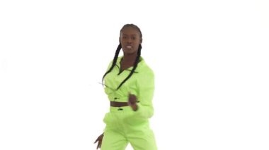 Genç Afrikalı kadın geleneksel afro hareketlerle dans ediyor. Neşeli dansçı, ritmik olarak ellerini sağa sola hareket ettiriyor. Beyaz arkaplanda izole.