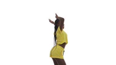 Seksi Afrikalı dans eden kadın elini kaldırıyor, kalçalarını çeviriyor ve etrafında dönüyor. Beyaz arkaplanda izole.