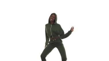Afro sokak dansı tarzında kapüşonlu Afrikalı Amerikalı kadın. Dönüşümlü olarak farklı taraflarda hareket eden, dizleri içeri ve dışarı iten, ritmik olarak kalçaları hareket ettiren. Beyaz arkaplanda izole.