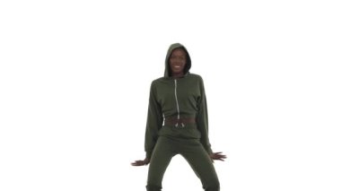 Kapüşonlu spor takım elbiseli Afro-Amerikalı kadın sokak dansı tarzında doğaçlama yapıyor. B- kız dönen vücut, ritmik olarak hareket eden eller ve kalçalar. Serbest stil dansı. Beyaz arkaplanda izole.