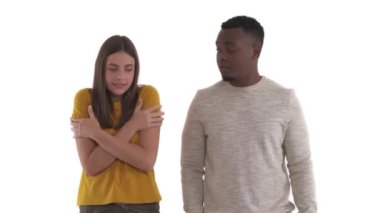 Kafkasyalı genç bir kadının portresi donuyor ve Afrikalı bir adam onu kollarında ısıtmaya çalışıyor. Romantik ilgi kavramı. Beyaz arkaplanda izole.