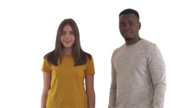 Irklar arası genç çift birine gülüyor ve kamerayı işaret ediyor. Beyaz arkaplanda izole.