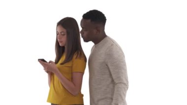 Meraklı Afrikalı bir adamın portresi cep telefonuyla yazı yazan beyaz kız arkadaşını dikizleyip kafa karışıklığını ifade ediyor. Beyaz arkaplanda izole