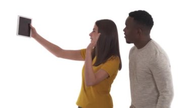 Arkadaşlarıyla ya da akrabalarıyla dijital tablet kullanarak konuşan ırklar arası çiftlerin yan görüntüsü. El sallayarak selam ver jestine. Şehirlerarası iletişim. Beyaz arkaplanda izole