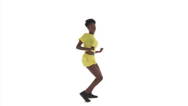 年轻的跳舞的非洲女人的全长肖像 女士扭动身体 把膝盖推入推出 做侧步 因白人背景而被隔离 — 图库视频影像