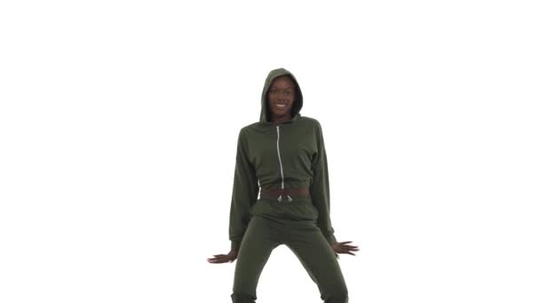 フード付きスポーツスーツを着たアフリカ系アメリカ人女性がストリートダンス風に即興で踊る Bの女の子の体のねじれ リズミカルに手と腰を移動します フリースタイルダンス 白地に隔離された — ストック動画