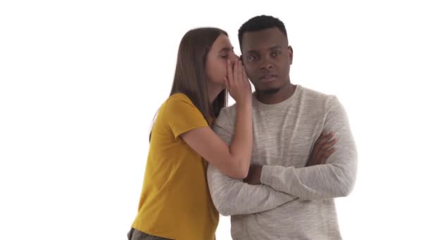 백인젊은 여자가 이야기를 속삭이거나 아프리카놀란 남자에게 비밀을 털어놓았습니다 배경에 고립됨 — 비디오
