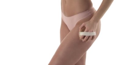 İnce beyaz kadın kalçasına ahşap fırçayla masaj yapıyor. Vücut bakımı konsepti. Kopya alanı ile beyaz arkaplanda izole.