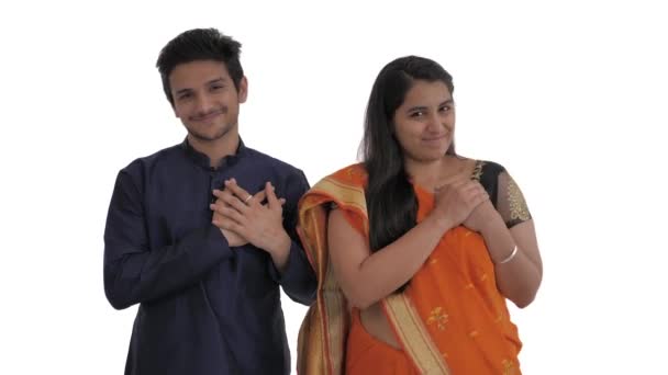 胸に手をつないでカメラに持ち上げることで誰かに同情と感謝の気持ちを表すかわいいインドのカップルの肖像画 白地に隔離された — ストック動画