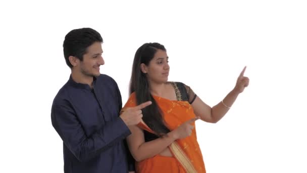 这对年轻的印度夫妇赞同地指着右边 普通的印地安语 因白人背景而被隔离 — 图库视频影像