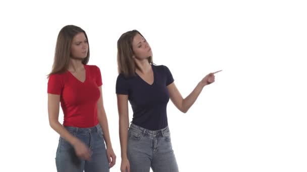 白人孪生姐妹用食指和点头指向右边 在带有复制空间的白色背景上隔离 — 图库视频影像