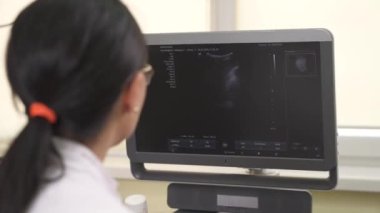 Tıbbi muayene sırasında ultrason makinesinin monitörüne bakan profesyonel bir kadın doktorun yakın çekimi. Sağlık hizmetleri kavramı