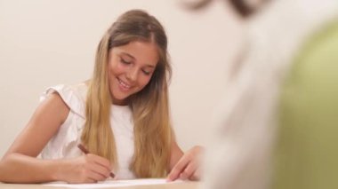 Güzel bir genç kızın portre resmi. Kalemlerle çiziyor ve bir terapistle konuşurken gülümsüyor. Olumlu duygular. Psikolog psikolojik test yapıyor..