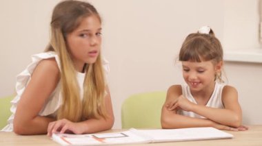İki neşeli mutlu kız kardeş resimlere bakıyor ve ne gördüklerini tartışıyorlar. Çocuk psikolojisi terapisi. Aile psikolojisi